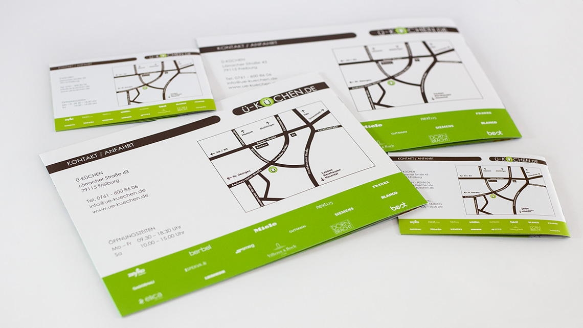 Ansicht mehrerer Rückseiten verschiedener Printprodukte von Ü-Küchen auf grauem Untergrund