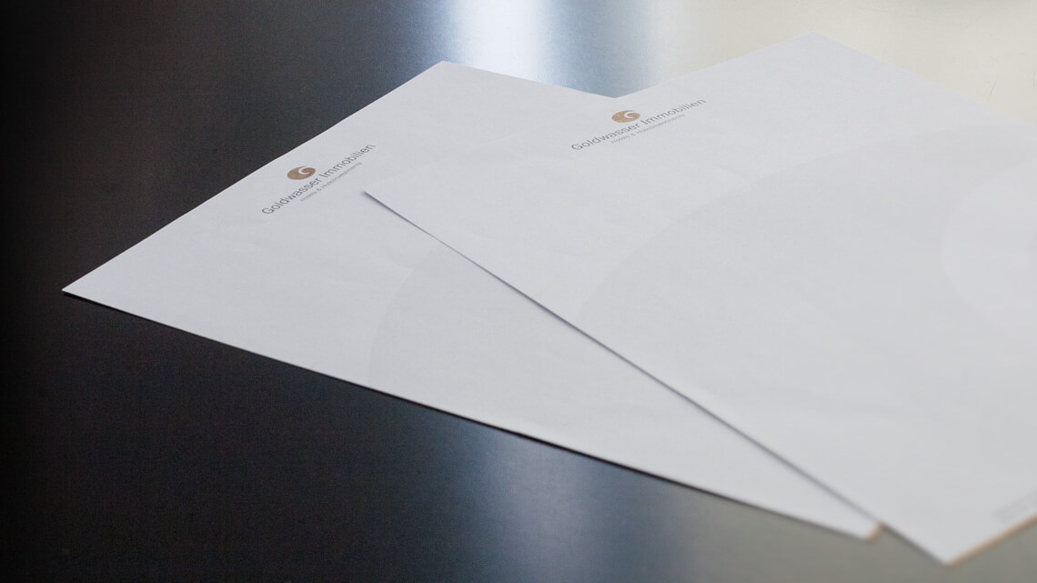 Ansicht der Briefpapiere von Goldwasser Immobilien auf einem dunklen Tisch
