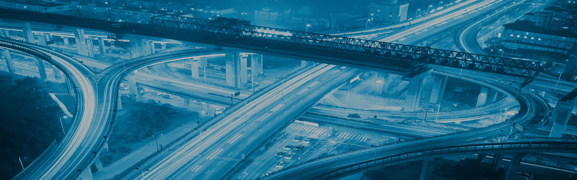 Luftaufnahme eines komplexen Autobahnkreuzes mit mehreren Überführungen und Auffahrten bei Nacht unter einem blauen Filter