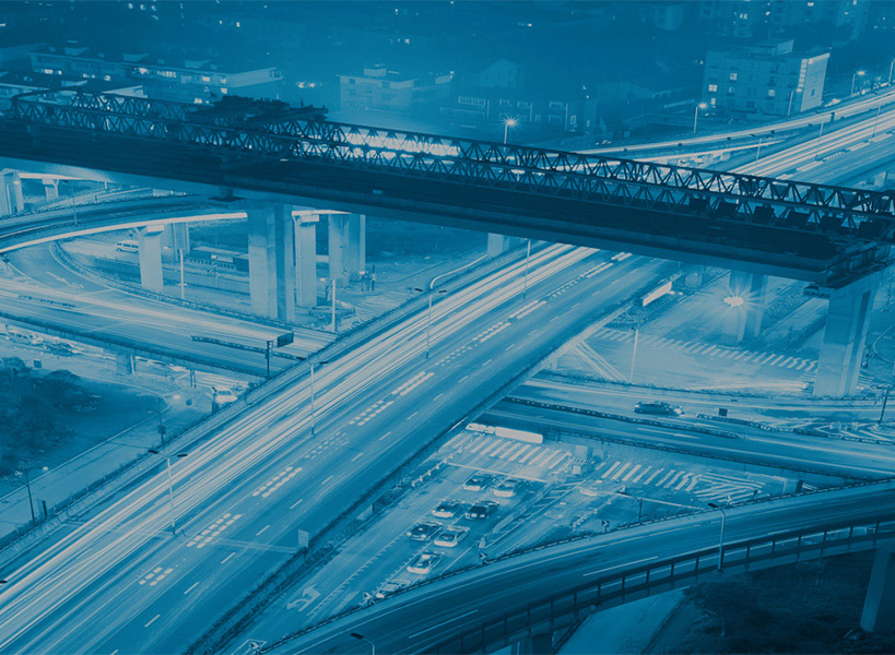 Luftaufnahme eines komplexen Autobahnkreuzes mit mehreren Überführungen und Auffahrten bei Nacht unter einem blauen Filter