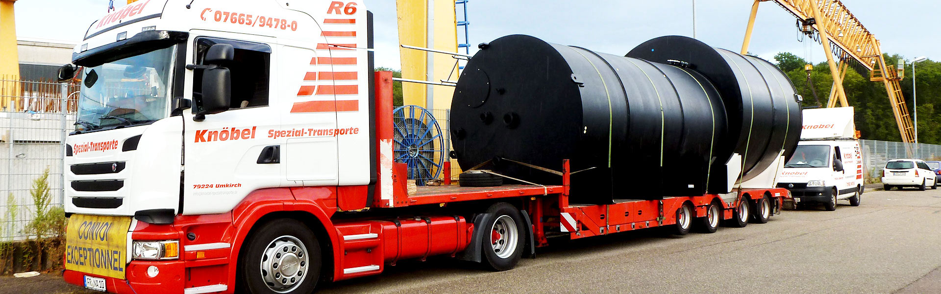 Rot-weißer LKW von Knöbel transportiert zwei große schwarze Zylindertanks