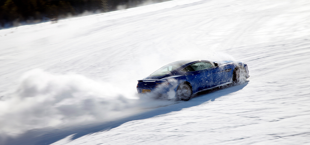Blauer Sportwagen, der auf einem flockigen Schneefeld driftet