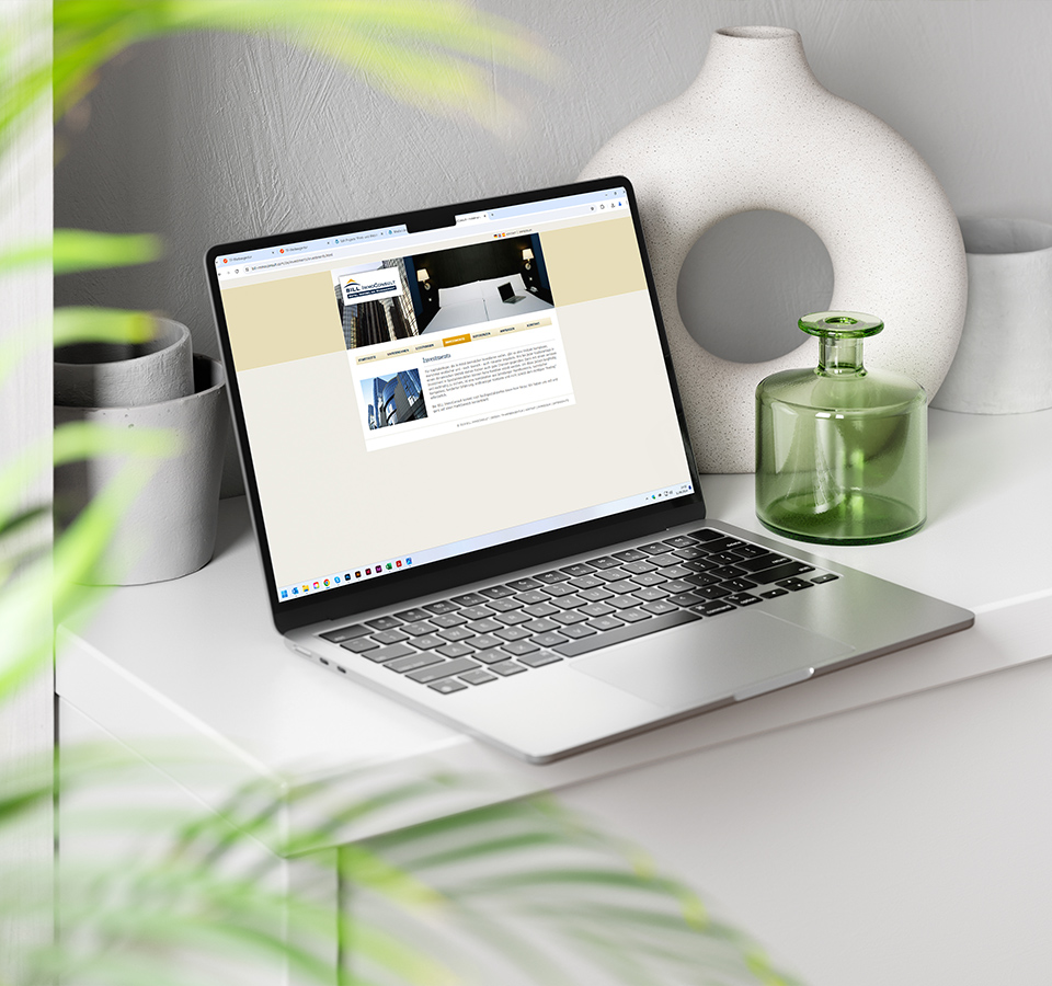 Ansicht der Webseite von BILL ImmoConsult auf einem Notebook in einem modern eingerichteten Zimmer mit Pflanzen