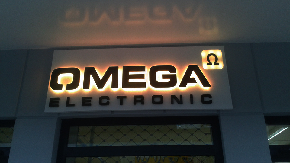 Ansicht der Front der Filiale von Omega Electronics mit dem von hinten beleuchteten Logo über dem Eingang