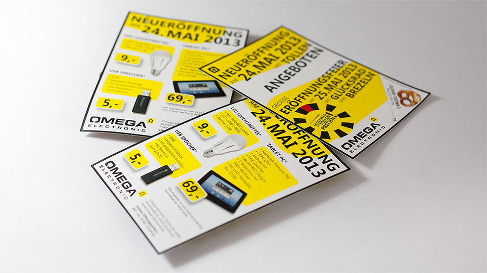 Ansicht dreier Flyer im Corporate Design von Omega Electronics auf einem weißen Tisch