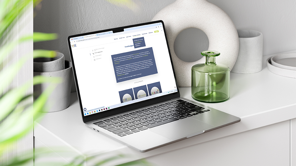 Ansicht der Webseite von ICSE auf einem Notebook in einem modern eingerichteten Raum, im Vordergrund Pflanzen