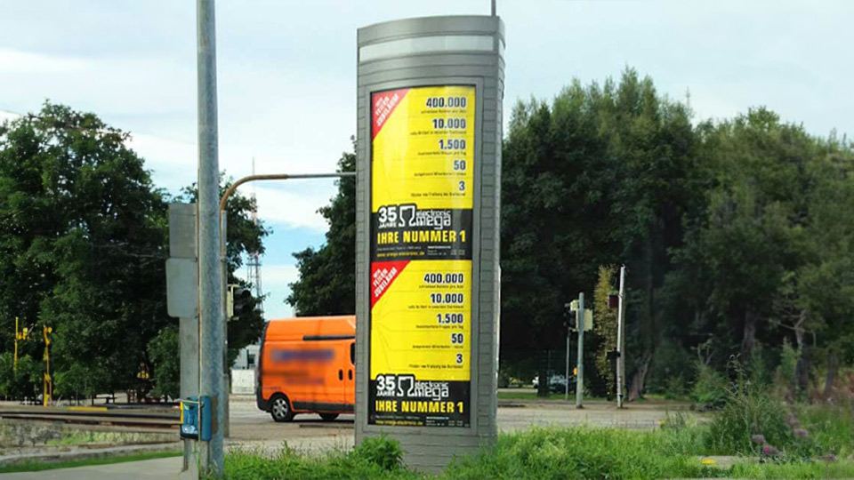 Ansicht Citylight von Omega Electronics an einer befahrenen Straße mit Bäumen im Hintergrund